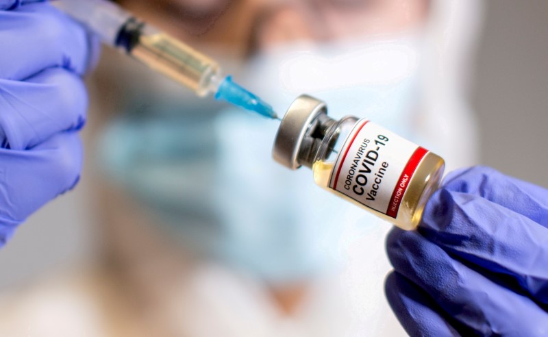&copy; Reuters. FILE PHOTO: A woman holds a small bottle labelled with a "Coronavirus COVID-19 Vaccine" sticker and a medical syringe in this illustration taken  October 30, 2020. REUTERS/Dado Ruvic