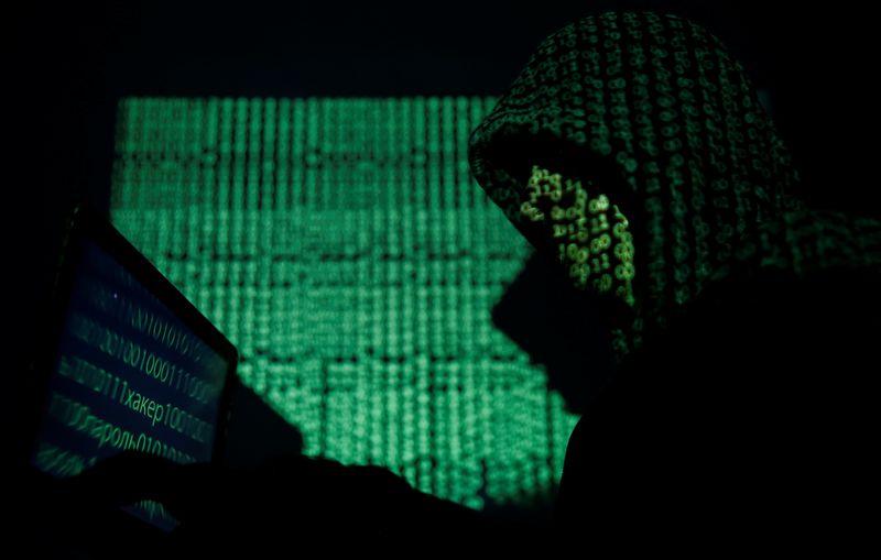 &copy; Reuters. FILE PHOTO: A hooded man holds a laptop computer as cyber code is projected on him in this illustration picture taken on May 13, 2017. REUTERS/Kacper Pempel/Illustration