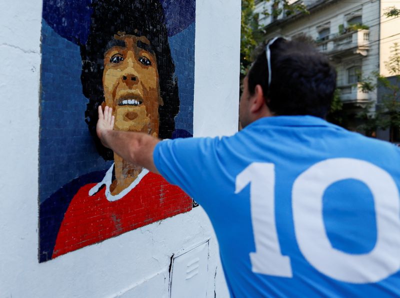 © Reuters. رجل يضع يده على لوحة فسيفساء عليها صورة لاعب كرة القدم الأرجنتيني دييجو مارادونا في بوينس أيرس بصورة من أرشيف رويترز.