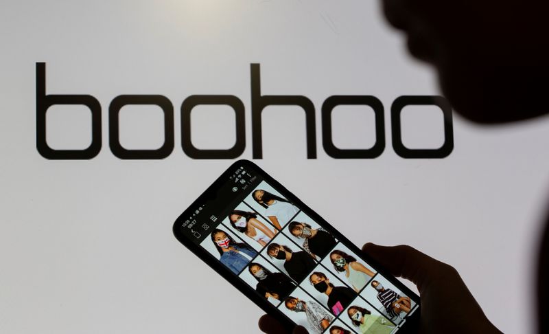 &copy; Reuters. FILE PHOTO: A woman poses with a smartphone showing the Boohoo app in front of the Boohoo logo on display in this illustration taken September 30, 2020. REUTERS/Dado Ruvic/Illustration/File Photo
