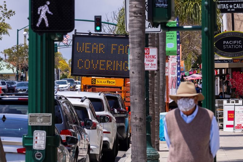 &copy; Reuters. FILE PHOTO: A man walks down a street in Encinitas, as California Governor Gavin Newsom said his state would keep its mask order in place for another month, in California, U.S., May 17, 2021. REUTERS/Mike Blake