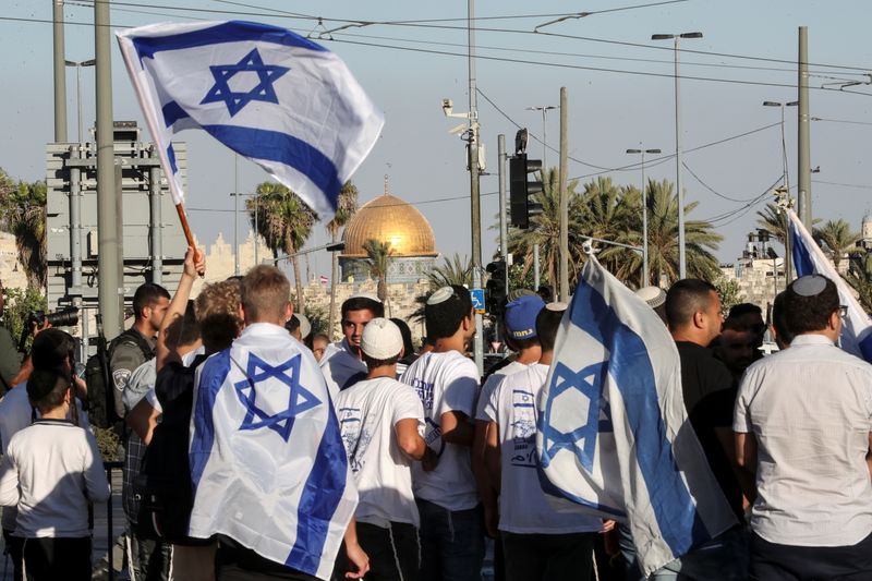 © Reuters. Israelis walk with flags outside Jerusalem's Old City,  June 15,2021. REUTERS/Ronen Zvulun