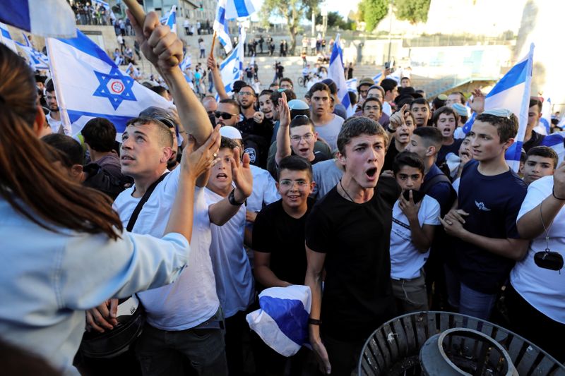 © Reuters. إسرائيليون يلوحون بأعلام إسرائيلية عند بوابة دمشق خارج البلدة القديمة في القدس أثناء مسيرة يوم الثلاثاء. تصوير: عمار عوض - رويترز.