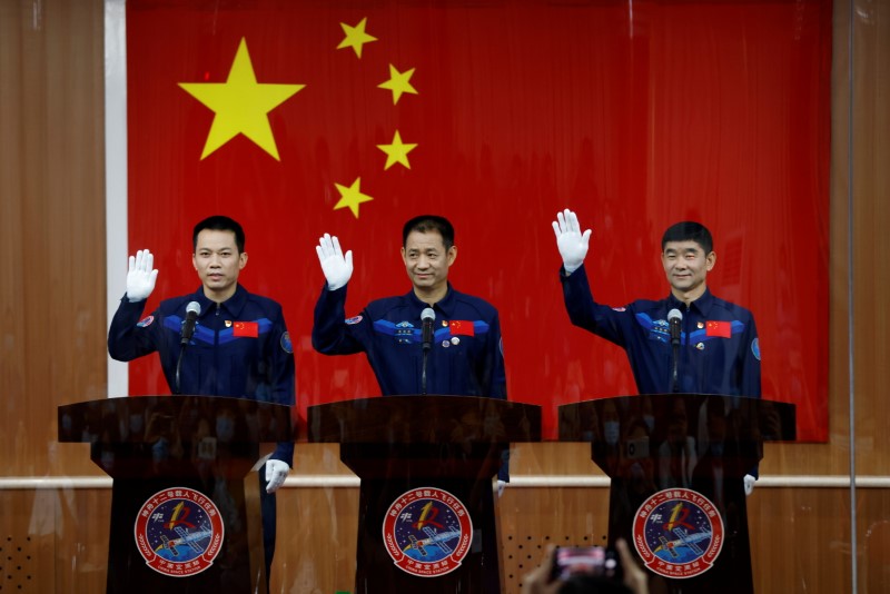 &copy; Reuters. Chinese astronauts Nie Haisheng, Liu Boming, and Tang Hongbo wave as they meet members of the media behind a glass wall before the Shenzhou-12 mission to build China's space station, at Jiuquan Satellite Launch Center near Jiuquan, Gansu province, China J