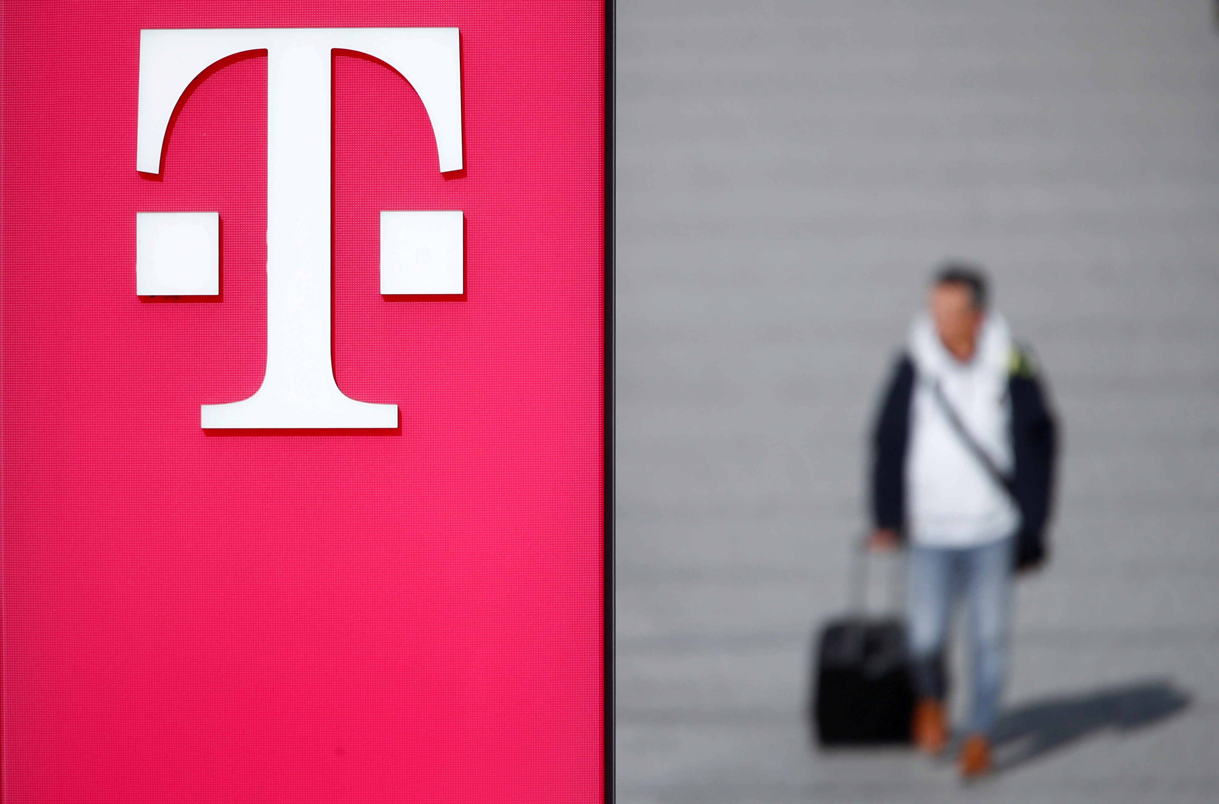 &copy; Reuters. FILE PHOTO: A man walks past the logo of Deutsche Telekom AG at the headquarters of German telecommunications giant in Bonn, Germany, February 19, 2019. REUTERS/Wolfgang Rattay/File Photo