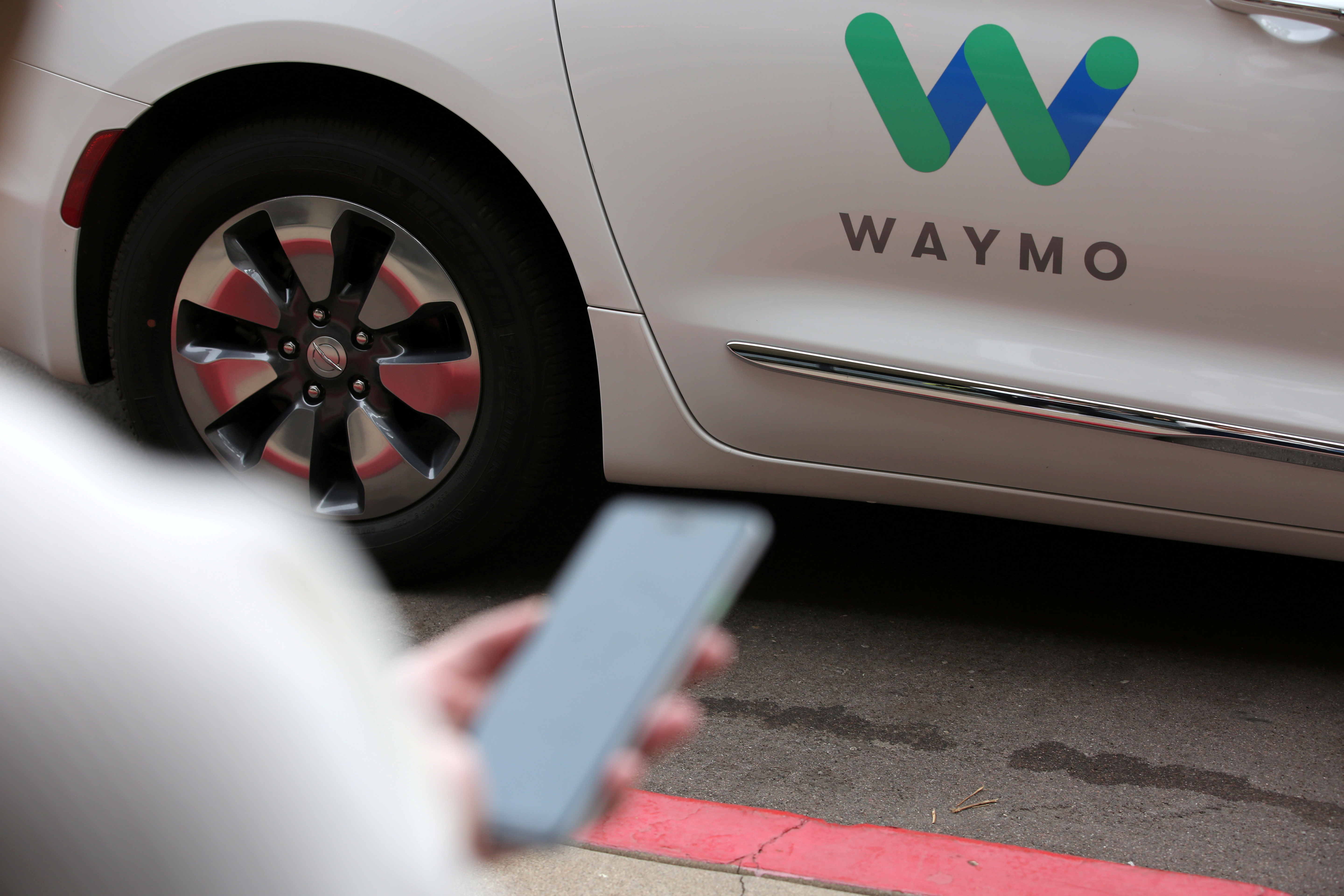 &copy; Reuters. FILE PHOTO: A Waymo employee hails a ride on their phone during a demonstration in Chandler, Arizona, November 29, 2018.  REUTERS/Caitlin O’Hara/File Photo