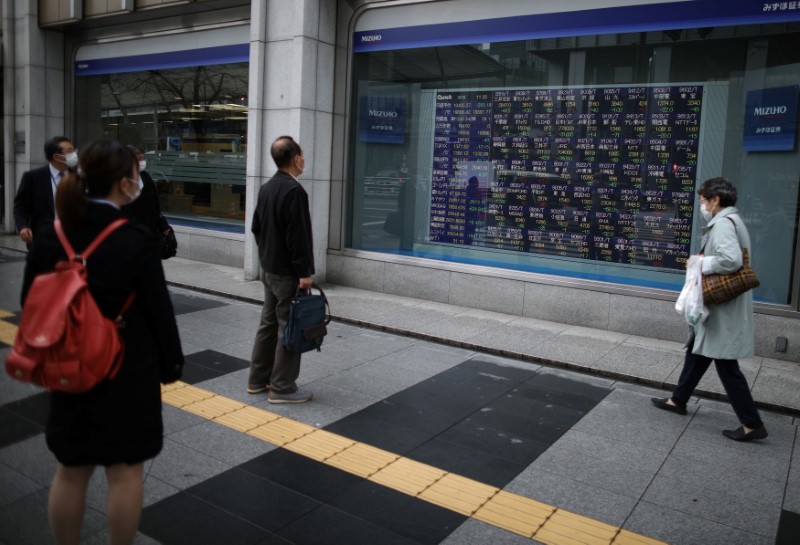&copy; Reuters. People wearing protective face masks, following an outbreak of the coronavirus disease (COVID-19), look at a stock quotation board outside a brokerage in Tokyo, Japan, March 10, 2020. REUTERS/Stoyan Nenov/Files