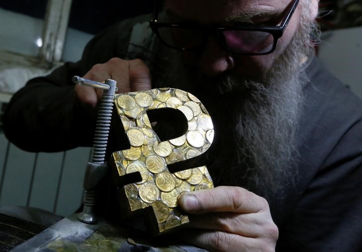 &copy; Reuters. Russian artist Vasily Slonov works on his artwork "Rouble Saving Project", which depicts the sign of the Russian rouble, at a workshop in Krasnoyarsk, Russia in this picture illustration taken January 10, 2019. REUTERS/Ilya Naymushin/Illustration