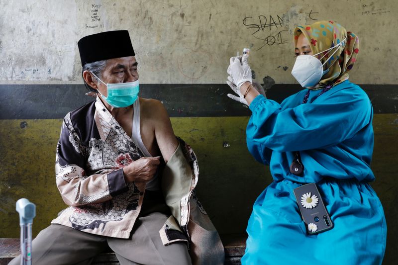 &copy; Reuters. Lili Dinata, 72-year-old local of Sindanglaya village, prepares to receives his first dose of a COVID-19 vaccine, during a door-to-door vaccination in Cianjur regency, West Java province, Indonesia, June 15, 2021. REUTERS/Willy Kurniawan