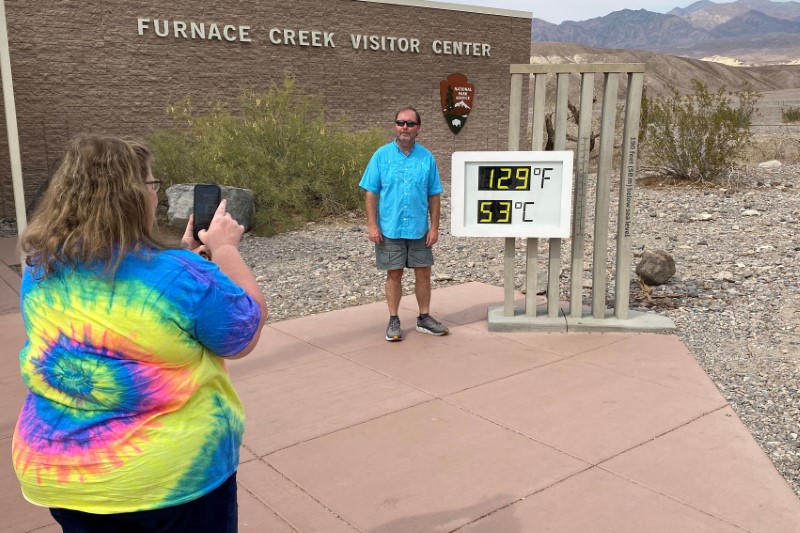© Reuters. Patrick Fox, 63, from Utah poses for a picture next to the thermometer at the Furnace Creek Visitor Center at Death Valley National Park, with the temperature showing at 129 degrees Fahrenheit (53.8 C) in Death Valley, California, U.S. June 16, 2021. Picture taken June 16, 2021.  REUTERS/Norma Galeana
