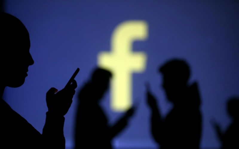 &copy; Reuters. Silhouettes of mobile users are seen next to a screen projection of Facebook logo in this picture illustration taken March 28, 2018.  REUTERS/Dado Ruvic/Illustration