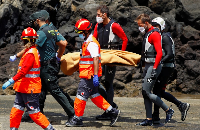 © Reuters. أفراد في خدمات الانقاذ يحملون جثمان أحد المهاجرين في جزيرة لانساروتي بإسبانيا يوم الجمعة. تصوير: بورخا سواريز - رويترز. 