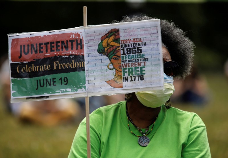 © Reuters. Norma Ewing of Seattle holds a sign as people gather at Judkins Park for Juneteenth, which commemorates the end of slavery in Texas, two years after the 1863 Emancipation Proclamation freed slaves elsewhere in the United States, in Seattle, Washington, U.S. June 19, 2020.  REUTERS/Lindsey Wasson