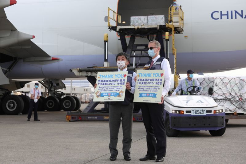 © Reuters. Taiwan's Health Minister Chen Shih-chung and top U.S. diplomat in Taiwan, Brent Christensen, pose for pictures in front of a China Airlines airplane carrying Moderna vaccines against the coronavirus disease (COVID-19) shipped from the United States, at Taoyuan International airport in Taoyuan, Taiwan, June 20, 2021. Taiwan Centers for Disease Control/Handout via REUTERS 