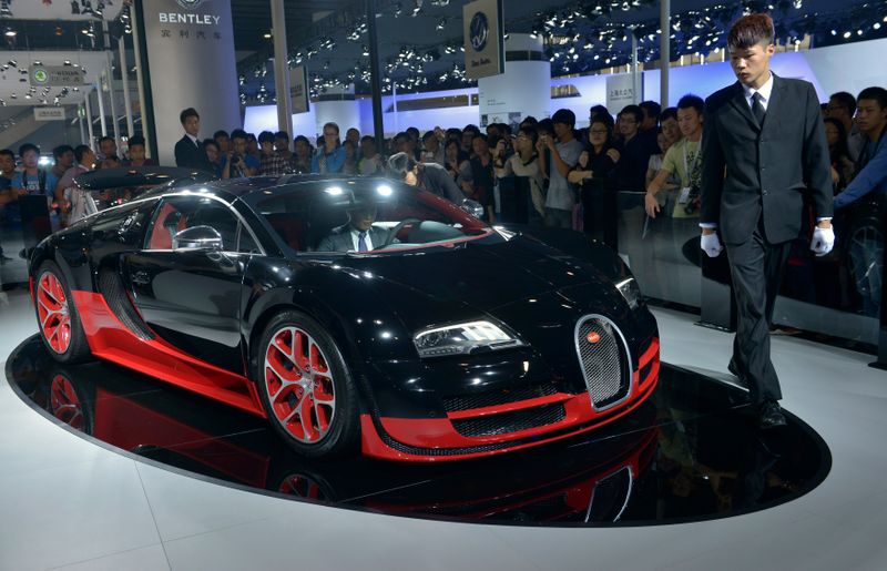 &copy; Reuters. A site organizer walks by a Bugatti Veyron at the Guangzhou International Automobile Exhibition in Guangzhou, Guangdong province, November 22, 2013. Luxury car dealers are resorting to offering customers massages, mini-golf and other gimmicks, hoping this