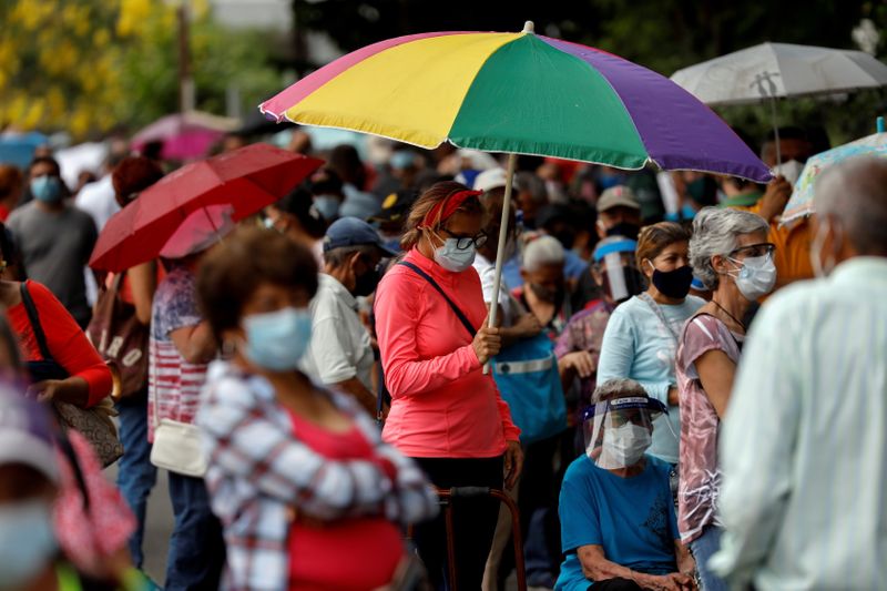 &copy; Reuters. FILE PHOTO: A woman with an umbrella waits with her mother on a street outside the Regional Government Health Corporation turned into a mass vaccination centre to receive their first dose of Russia's Sputnik V vaccine against the coronavirus disease (COVI