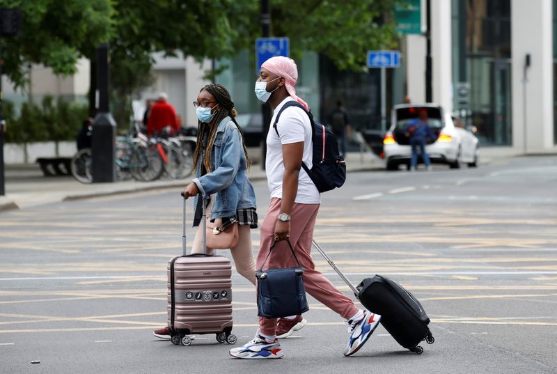 &copy; Reuters. Personas llevan mascarillas protectoras mientras caminan con maletas por el centro de Manchester, Reino Unido, el 21 de junio de 2021. REUTERS/Phil Noble
