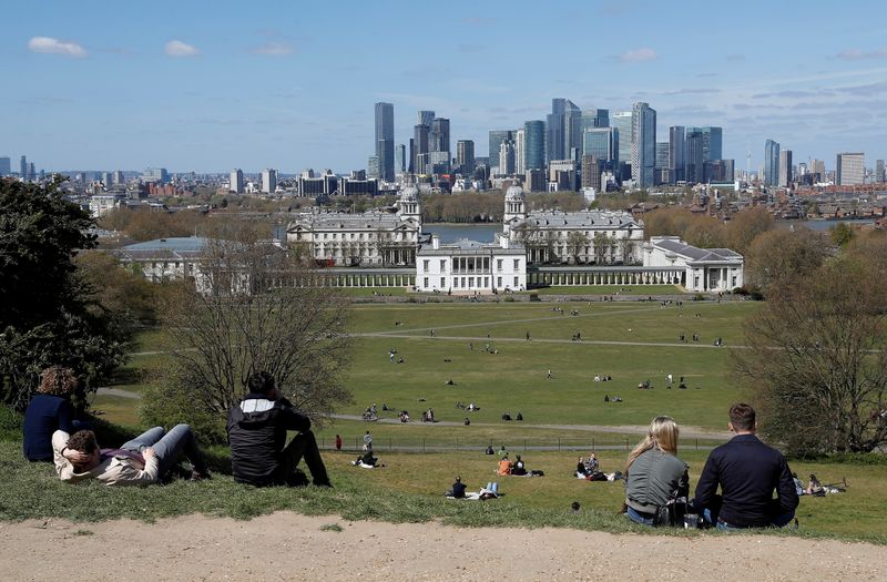 &copy; Reuters. Visitors to Greenwich Park sit and look towards Canary Wharf financial district as lockdown restrictions are eased amidst the spread of the coronavirus disease (COVID-19) pandemic in London, Britain, April 25, 2021. REUTERS/Peter Nicholls/File Photo