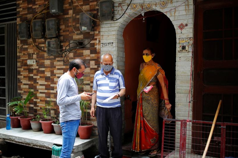 &copy; Reuters. Un voluntario de la ONG SEEDS ayuda a una pareja a registrarse para la vacunación contra la COVID-19 frente a la casa de ambos en Nueva Delhi, India, el 16 de junio de 2021. REUTERS/Adnan Abidi