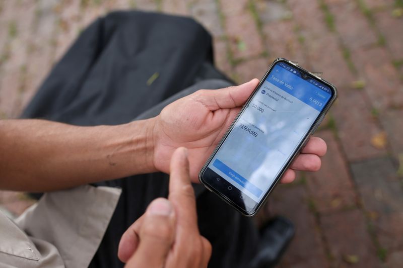 © Reuters. Pablo Toro, Venezuelan delivery worker uses the Valiu application from his cell phone to check the exchange rate from dollars to Bolivares, in Bogota, Colombia June 15, 2021. Picture taken June 15, 2021. REUTERS/Luisa Gonzalez