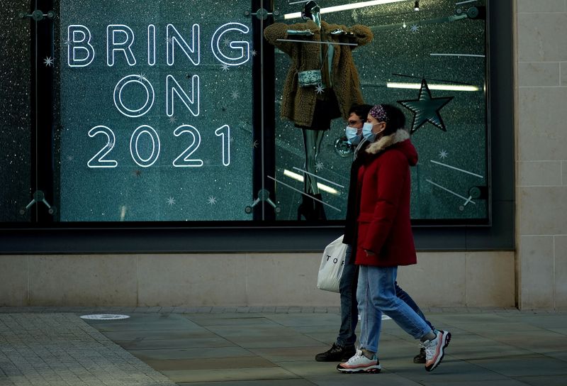&copy; Reuters. FILE PHOTO: People walk past a sign in a shop window amid the outbreak of the coronavirus disease (COVID-19) in Manchester, Britain, December 15, 2020. REUTERS/Phil Noble/File Photo