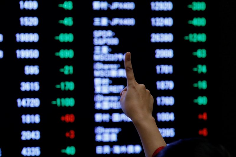 &copy; Reuters. A woman points to an electronic board showing stock prices as she poses in front of the board after the New Year opening ceremony at the Tokyo Stock Exchange (TSE), held to wish for the success of Japan's stock market, in Tokyo, Japan, January 4, 2019. RE