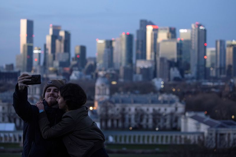 &copy; Reuters. FILE PHOTO: A couple poses for a selfie photograph towards Canary Wharf from Greenwich Park in London, Britain December 27, 2020. REUTERS/Simon Dawson/File Photo