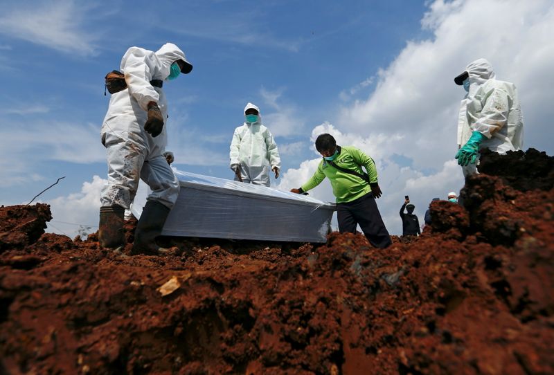 &copy; Reuters. عمال البلدية يرتدون معدات وقائية شخصية يستعدون لدفن كفن أحد ضحايا كوفيد-19 في جاكرتا بصورة من أرشيف رويترز.