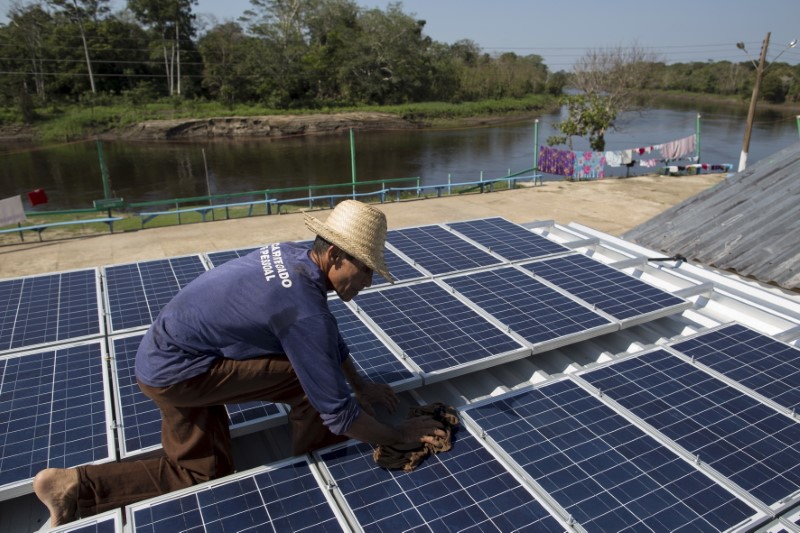 &copy; Reuters. Homem checa painéis de energia solar instalados em Vila Nova do Amanã (AM) 
22/09/2015
REUTERS/Bruno Kelly