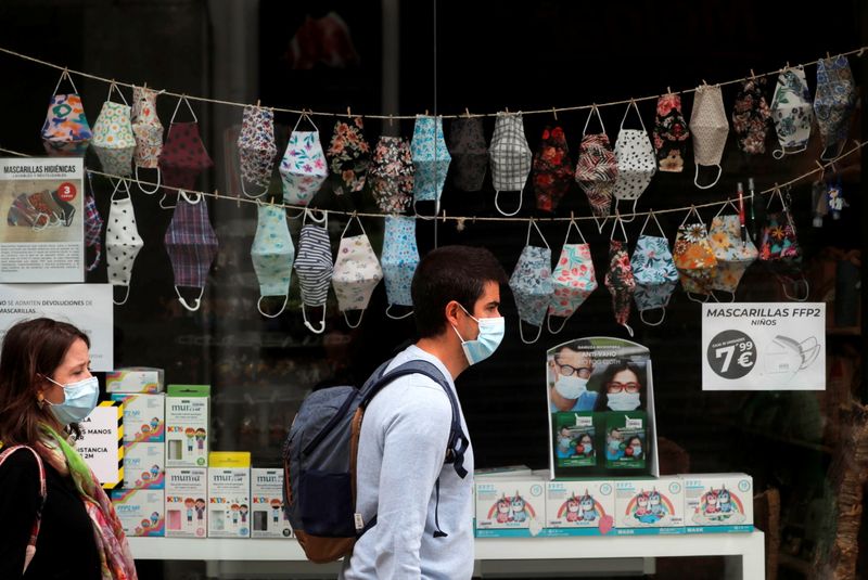 &copy; Reuters. FILE PHOTO: People wear protective masks as they walk past to a souvenir shop with masks displayed, after Spanish Prime Minister Pedro Sanchez announced on Friday, the lifting of the blanket obligation to wear masks outdoors from June 26, amid the coronav