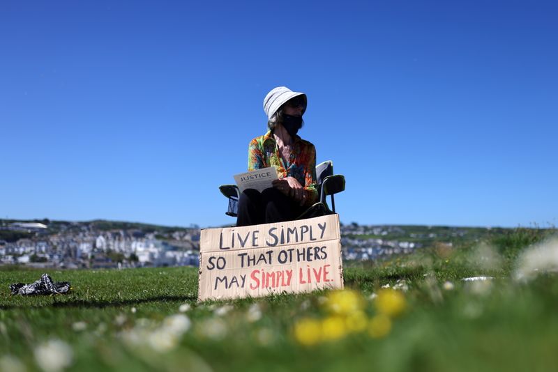 &copy; Reuters. FILE PHOTO: A No Going Back Sundays activist sits next to a placard as they take part in a demonstration for racial, climate, social and nature justice, at the Island in St Ives, during the G7 summit in Cornwall, Britain, June 13, 2021. REUTERS/Tom Nichol