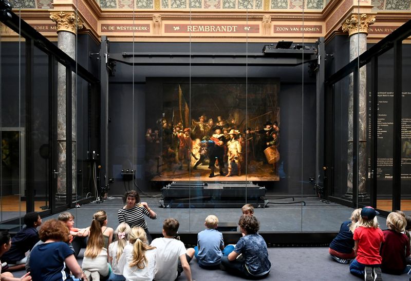 &copy; Reuters. Children look at Rembrandt's famed Night Watch, which is back on display in what researchers say in its original size, with missing parts temporarily restored in an exhibition aided by artificial intelligence, at Rijksmuseum in Amsterdam, Netherlands June