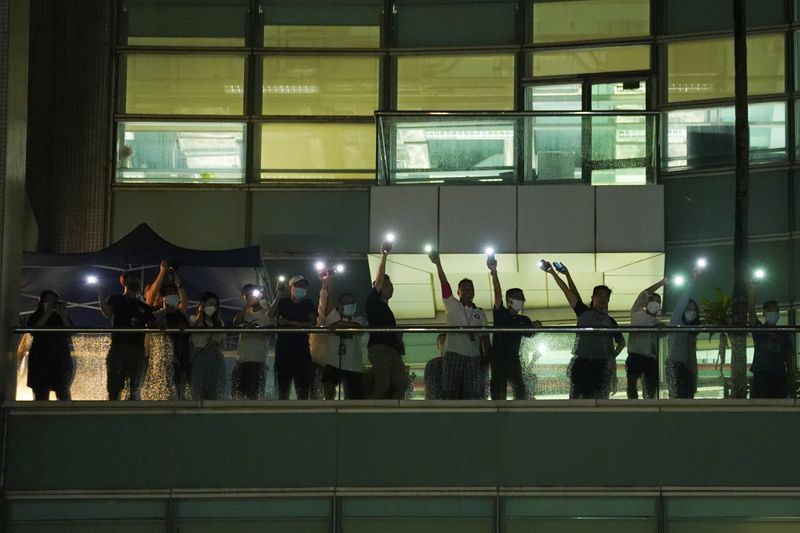 &copy; Reuters. Personas encienden las linternas de sus teléfonos y saluda a sus seguidores en la sede del periódico Apple Daily, y su editor Next Digital, tras el anuncio de que imprimirá su última edición, en Hong Kong, China el 23 de junio de 2021. REUTERS/Lam Yi