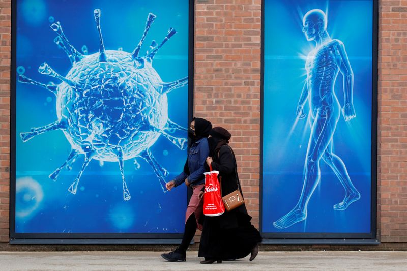 &copy; Reuters. امرأتان تسيران أمام رسم توضيحي لفيروس كورونا في بريطانيا بصورة من أرشيف رويترز.