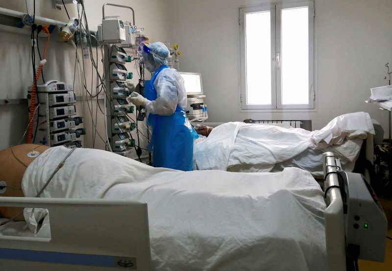 &copy; Reuters. أحد أفراد الطاقم الطبي يساعد مريض مصاب بفيروس كورونا في مستشفى بمدينة آريانة التونسية يوم 26 أبريل نيسان 2021. صورة لرويترز.