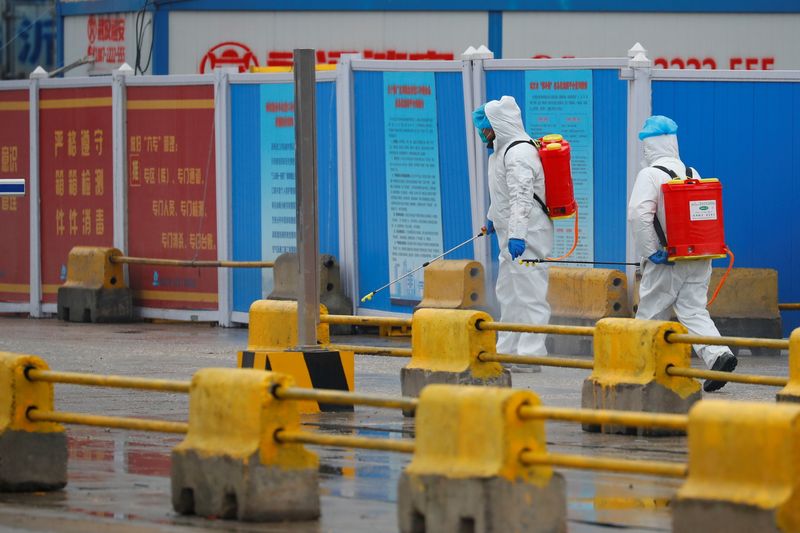 &copy; Reuters. FILE PHOTO: Workers in PPE spray the ground with diinfectant in Baishazhou market during a visit of World Health Organization (WHO) team tasked with investigating the origins of the coronavirus (COVID-19) pandemic, in Wuhan, Hubei province, China, January