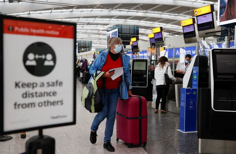&copy; Reuters. FOTO DE ARCHIVO: Una pasajera con mascarilla camina con su maleta por el área de salidas de la Terminal 5 del aeropuerto de Heathrow en Londres, Reino Unido, el 17 de mayo de 2021. REUTERS/John Sibley