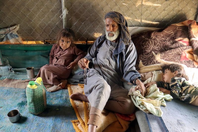 &copy; Reuters. علي النهمي يجلس مع حفيده في معسكر للنازحين داخليا في محافظة مأرب في اليمن يوم 5 أبريل نيسان 2021. تصوير: علي عويضة - رويترز  