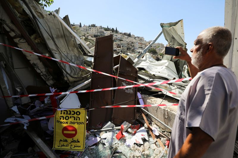 &copy; Reuters. A Palestinian man uses his mobile phone as he stands near the debris of a shop that Israel demolished in the Palestinian neighbourhood of Silwan in East Jerusalem June 29, 2021. REUTERS/Ammar Awad