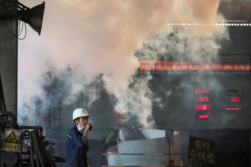 © Reuters. FILE PHOTO: A worker stands near smoke from blast furnace at the Chongqing Iron and Steel plant in Changshou, Chongqing, China August 6, 2018. REUTERS/Damir Sagolj