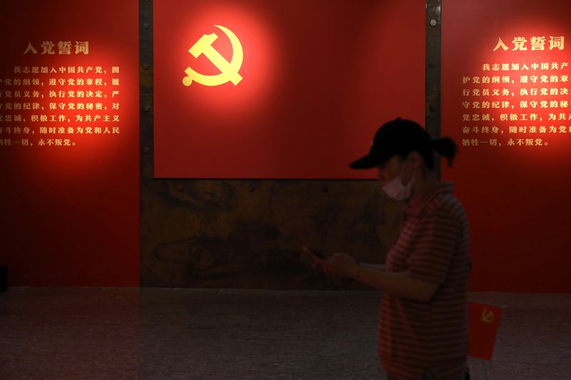 &copy; Reuters. A visitor walks past a board with an emblem of the Communist Party of China at an exhibition marking the 100th anniversary of the founding of the Party, in Beijing, China June 22, 2021. Picture taken June 22, 2021. REUTERS/Tingshu Wang