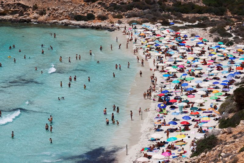 &copy; Reuters. FILE PHOTO: People sunbathe on the beach on the Sicilian island of Lampedusa, as a flow of migrants arriving on the Mediterranean island, in Lampedusa, Italy, June 22, 2021. REUTERS/Guglielmo Mangiapane  