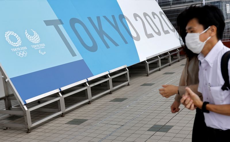 &copy; Reuters. People walk past a sign for the 2020 Tokyo Olympic Games that have been postponed to 2021 due to the coronavirus disease (COVID-19) pandemic, at the IBC/MPC media center at Tokyo Big Sight exhibition center in Tokyo, Japan June 30, 2021.  REUTERS/Fabrizio