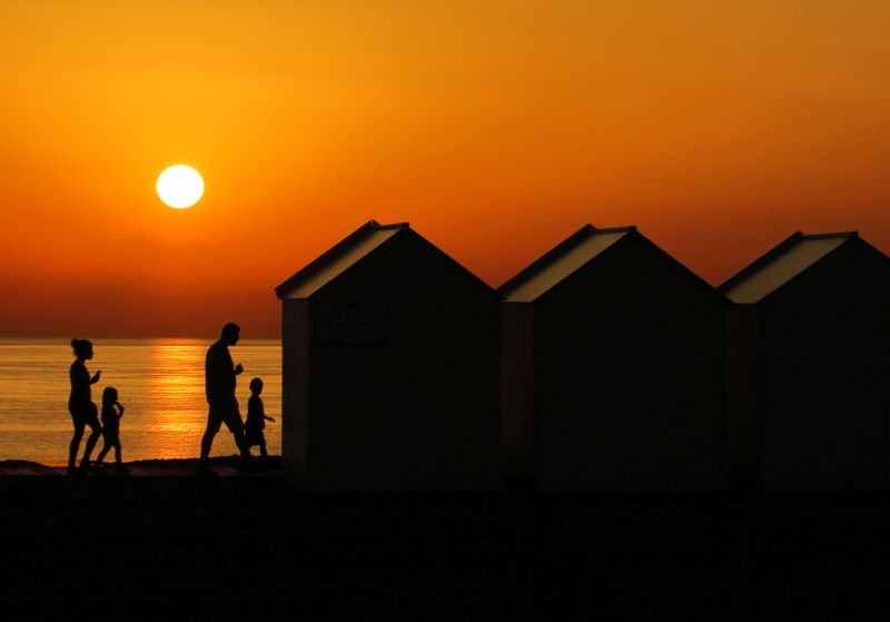 &copy; Reuters. FILE PHOTO: A family walks beside beach cabins on a pebbled beach, during sunset as a heatwave hits France, in Cayeux-sur-Mer, France, June 29, 2019. REUTERS/Pascal Rossignol/File Photo