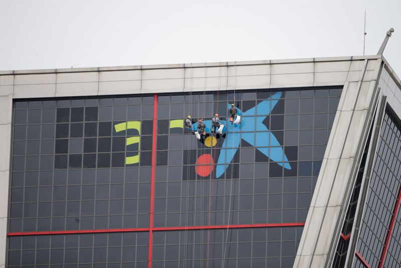 &copy; Reuters. Trabajadores sustituyen el cartel del banco español Bankia, tras la fusión con su rival Caixabank, en su sede de la torre Puerta de Europa, en Madrid, España, 27 de marzo de 2021. REUTERS/Javier Barbancho