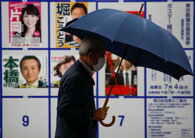 © Reuters. A voter wearing a protective face mask walks past a board displaying posters of candidates for the Tokyo Metropolitan Assembly election near a polling station, amid the coronavirus disease (COVID-19) outbreak, in Tokyo, Japan July 4, 2021.  REUTERS/Issei Kato