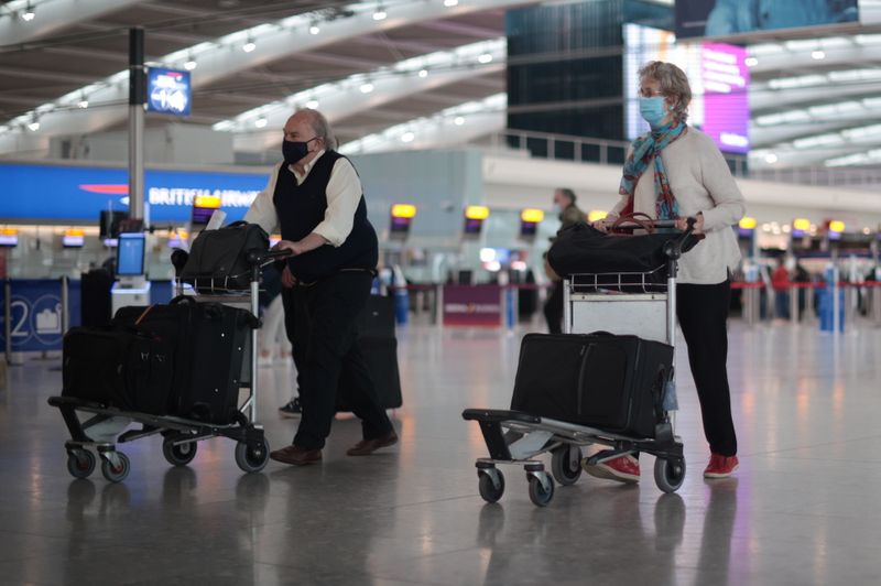 &copy; Reuters. راكبان يضعان الكمامة ويسيران في منفذ للمغادرة في مطار هيثرو بلندن يوم 12 يونيو حزيران 2021. تصوير: رويترز.