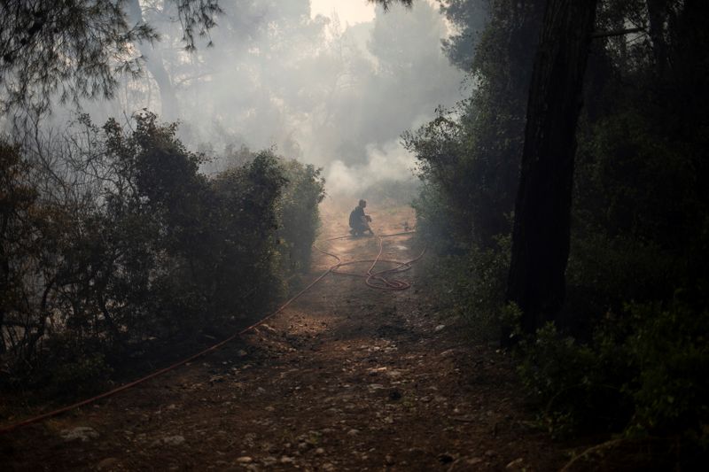 &copy; Reuters. FILE PHOTO: A firefighter pauses as he tries to extinguish a fire burning in the village of Mazi, near Corinth, Greece, May 20, 2021. REUTERS/Stelios Misinas/File Photo