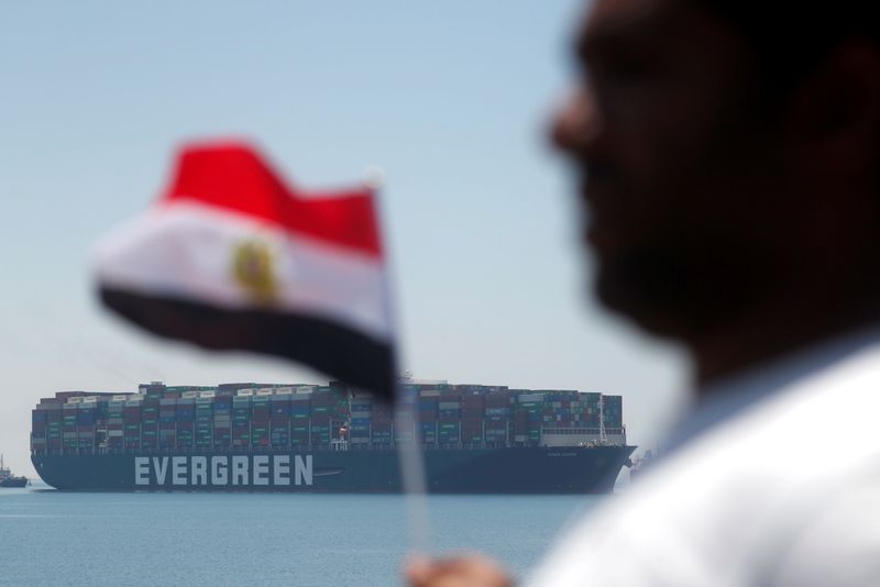 © Reuters. A man holds an Egyptian flag as Ever Given, one of the world's largest container ships, is seen at the Suez Canal after the canal authority reached a settlement with the vessel's owner and insurers, in Egypt's Great Bitter Lake in Ismailia, Egypt, July 7, 2021. REUTERS/Amr Abdallah Dalsh    