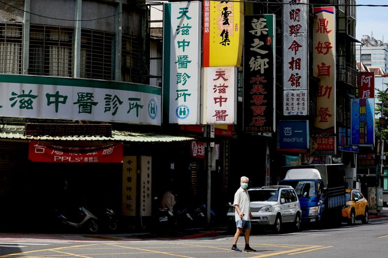&copy; Reuters. A man crosses the street while wearing a protective mask following the recent rise in coronavirus disease (COVID-19) infections in Taipei, Taiwan June 2, 2021. REUTERS/Ann Wang/Files